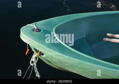 Nahansicht des Bogens des grünen Ruderboots, das nur die Griffenden der Oare und die Anlegseile gegen dunkelblaues Meerwasser zeigt Stockfoto