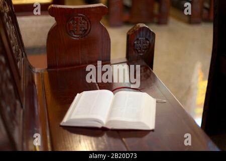 Öffnen Sie die heilige Bibel auf einer Holzbank in arabischer Sprache. Cristianität gegenüber islamischen Ländern Stockfoto