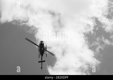 Schwarz-weißes Bild des Hubschraubers, der durch den Himmel fliegt