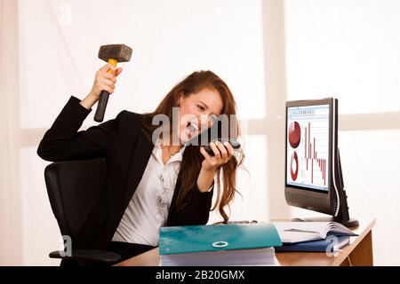 Wütende Geschäftsfrau, die Wut an ihrem Schreibtisch im Büro ausdrückt Stockfoto