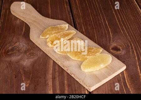 Gruppe von fünf Scheiben getrockneter gelber Ananas auf Holzschneidebrett auf braunem Holz Stockfoto
