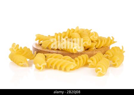 Viele ganze gelbe Nudelfusilli auf runder Bambusbahn isoliert auf weißem Hintergrund Stockfoto