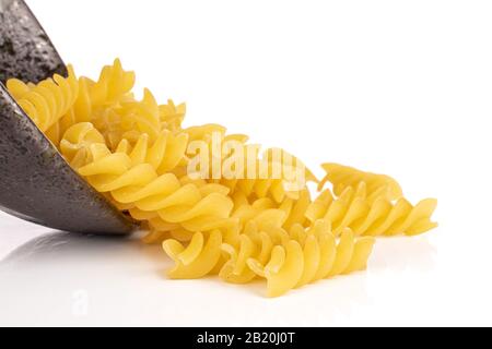 Viele ganze gelbe Nudelfusilli in glasierter Schüssel isoliert auf weißem Hintergrund Stockfoto