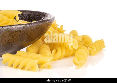 Viel ganz ungekochte gelbe Nudelfusilli in glasierter Schüssel isoliert auf weißem Hintergrund Stockfoto