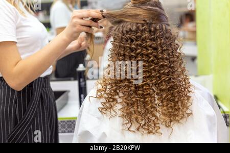 Haarschnitt Rückansicht. Friseursalon, der eine rote blonde Haarfrau mit langen Haaren im Schönheitssalon anstellt. Professionelle Haarpflege, Haarkleiden Stockfoto