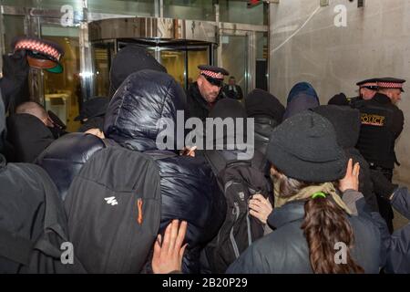 London, Großbritannien. Februar 2020. Die Polizei schimpft mit anarchistischen Demonstranten außerhalb der Londoner Börse. Verschiedene anarchistische und anti-kapitalistische Gruppen versammeln sich bei der Bank of England, bevor sie die Börse in Paternoster-Platz blockieren. Die Gruppen sind gegen das, was sie als willige Zerstörung der Ökosysteme der Erde und des kapitalistischen Systems ansehen, das diesen Prozess unterstützt. Penelope Barritt/Alamy Live News Stockfoto