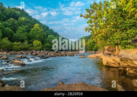 Am frühen Morgen scheint Sonnenaufgang auf den Felsen und Felsbrocken am Fluss Ocoee mit dem Wasser, das gerade aus dem Staudamm #2 herausströmt, der schnell flussabwärts fließt Stockfoto