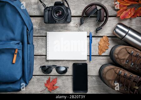 Ein Set von Materialien für Reisen auf einem Holzhintergrund, Notizblock. Leerraum in der Mitte. Stockfoto