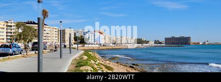 Horizontales Bild Strandpromenade entlang der Mittelmeer-Ferienort Torrevieja während des sonnigen warmen Tages blauer Himmel ruhiges Wasser, Costa Blanca, Spanien Stockfoto