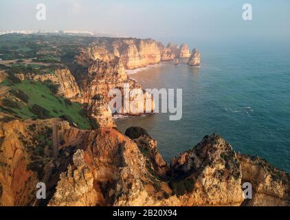 Luftpanorama auf der Landzunge Ponta da Piedade mit einer Gruppe von Felsformationen gelb-goldene Klippen entlang der Kalkküste, Lagos, Portugal Stockfoto