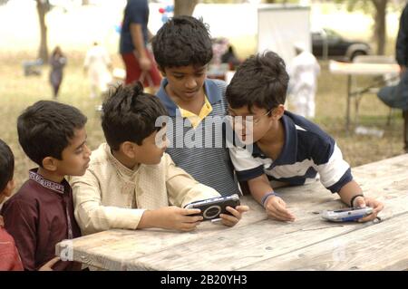 Austin, Texas 12. November 2005: Jungs spielen mit einem Sony PSP-Handheld-Spielgerät am Ende des Ramadan (Eid) Festivals für die muslimische Gemeinschaft in Zentral-Texas. Die Veranstaltung zeigt Essen, Tanz und Feste der muslimischen Welt. ©Bob Daemmrich Stockfoto