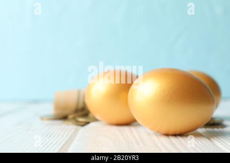 Goldene Eier und Geld auf blauem Hintergrund, Platz für Text Stockfoto