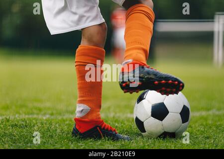 Fußball-Kick. Nahaufnahme der Beine und Füße des Fußballspielers in roten Socken und Stollen, die mit dem Ball laufen und dribbeln. Fußballspieler läuft ab Stockfoto