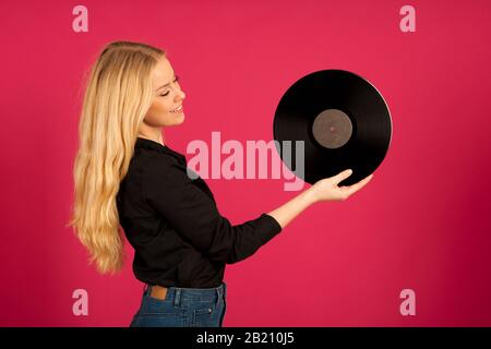 Schöne junge Frau, die eine Vinyl in den Händen hält, während sie die Musik hört Stockfoto