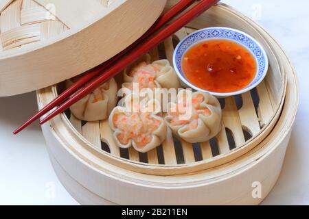 Dim Sum, gefüllte Knödel mit Essstäbchen und Chilisauce in Dampfkörben, Deutschland Stockfoto