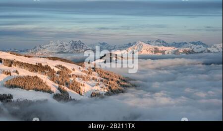 Bergpanorama mit Kitzbühler Horn und Loferer Steinbergen im Winter, Berggipfel über Wolkendecke im Abendlicht, SkiWelt Wilder Stockfoto
