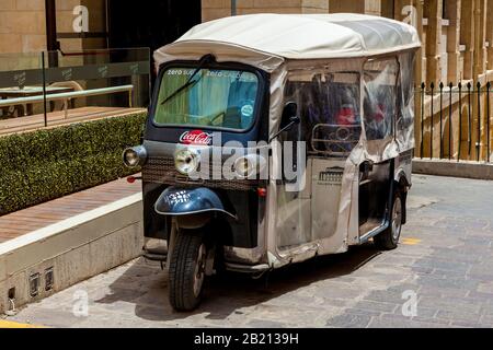 Malta Valletta 16. Juni 2019: Ein kleines Moto-Taxi wird an einem sonnigen Tag vor einem alten Gebäude geparkt. Stockfoto