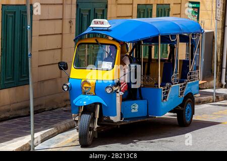 Malta Valletta 16. Juni 2019: Ein kleines Moto-Taxi wird an einem sonnigen Tag vor einem alten Gebäude geparkt. Stockfoto