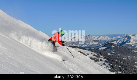 Skifahrer, die auf steilem Hang hinunterfahren, schwarze Piste, blauer Himmel, Berge dahinter, SkiWelt Wilder Kaiser, Brixen im Thale, Tyrol, Österreich Stockfoto