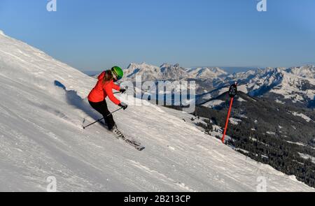 Skifahrer, die auf steilem Hang hinunterfahren, schwarze Piste, blauer Himmel, Berge dahinter, SkiWelt Wilder Kaiser, Brixen im Thale, Tyrol, Österreich Stockfoto