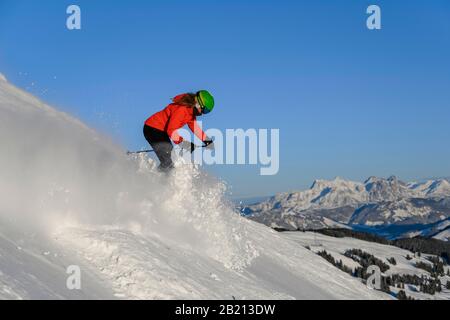 Skifahrer, die auf steilem Hang hinunterfahren, schwarze Piste, blauer Himmel, Berge dahinter, SkiWelt Wilder Kaiser, Brixen im Thale, Tyrol, Österreich Stockfoto