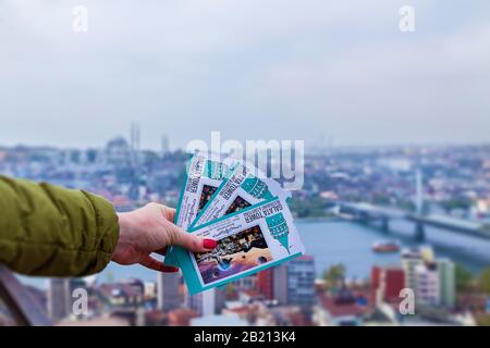 Türkei Alanya 18. April 2018: Eine Frau, die an einem sonnigen Tag Karten im Hintergrund eines Stadtpanoramas hält. Stockfoto