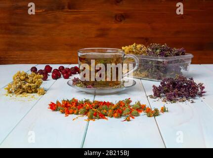 Frisch gebrühter Tee aus Heilkräutern. Getrocknete Heilkräuter für die Gesundheit. Lobaznik ordinary, oregano, marigalte Blumen, Rosehip auf einem Holztisch. Ph Stockfoto