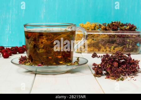 Frisch gebrühter Tee aus Heilkräutern. Getrocknete Heilkräuter für die Gesundheit. Lobaznik ordinary, oregano, marigalte Blumen, Rosehip auf einem Holztisch. Ph Stockfoto