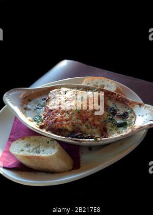 Genießen Sie Spinat und Pilzlasagna in einer cremigen alfredo Soße mit einer Seite französischem Brot Stockfoto