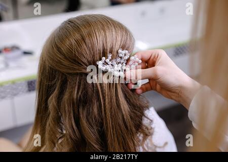 Haarschnitt Rückansicht mit Haarnadel. Friseursalon, der blonde Haarfrau mit langen Haaren im Schönheitssalon eine Frisur macht. Professionelle Haarpflege Stockfoto