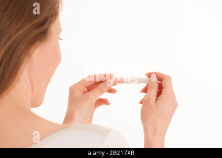 Glückliche Frau mit Schwangerschaftstest isoliert über weißem Hintergrund Stockfoto