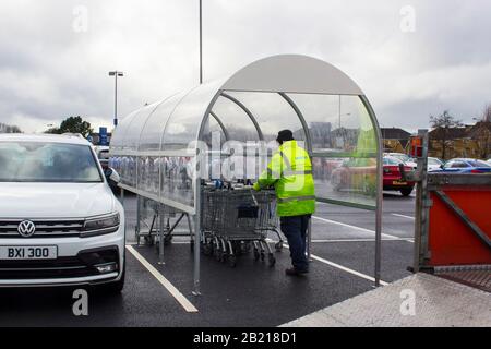 Februar 2020 EIN batteriebetriebenes Wanzi-Einkaufswagen-Rückgewinnungsfahrzeug bei der Arbeit vor Marks und Spencer im Parkplatz des Bloomfield Shopping Centers Stockfoto