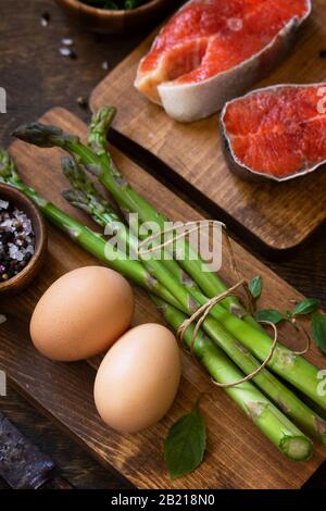Organische Lebensmittel. Kochkonzept für gesunde Lebensmittel. Lachs, Spargel und Eier auf einem rustikalen Tisch. Stockfoto