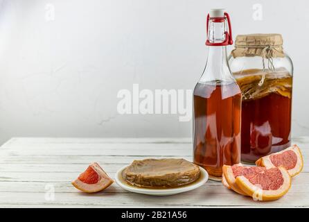 Kombucha Superfood pro biologischer Teepilz Getränk im Glasbecher mit Grapefruit auf weißem Hintergrund. Kopierraum Stockfoto