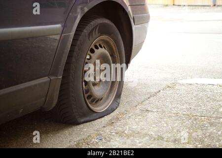 Flacher Reifen, beschädigtes Rad an Auto verloren Antenne Stockfoto