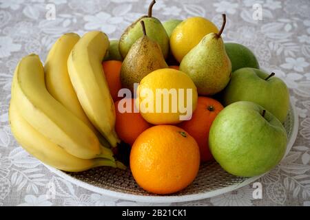 Früchte auf dem Teller. Verschiedene köstliche Früchte voller Vitamine und Antioxidantien, gelbe Zitronen und Bananen, grüne Äpfel und Birnen und orangefarbenes Orange Stockfoto