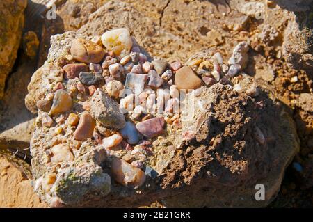 Verschiedene kleine bunte Steine in einem großen. Ansicht schließen. Stockfoto