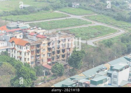 Brandneue und im Bau befindliche mehrstöckige Häuser im Vorort Hanoi, Vietnam. Luftbild urbane Ausbreitung mit grünen Metalldach-Häusern. Verfügbares Los si Stockfoto