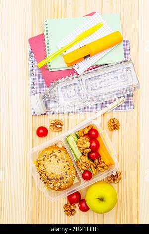 Schul-Mittagsbox mit Sandwich, frischem Obst, Gemüse, Wasser und Nüssen. Gesunde Essgewohnheiten für Kinder. Zurück zum Schulkonzept. Mit Schulbedarf Stockfoto