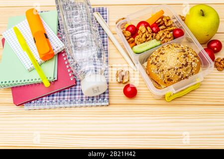 Schul-Mittagsbox mit Sandwich, frischem Obst, Gemüse, Wasser und Nüssen. Gesunde Essgewohnheiten für Kinder. Zurück zum Schulkonzept. Mit Schulbedarf Stockfoto