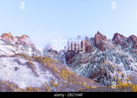 Maroon Bells Sonnenaufgang in Aspen, Colorado Red Elk Mountains mit felsigem Berg und Schnee im späten Herbst mit Winternebelwolkenbedeckung Stockfoto