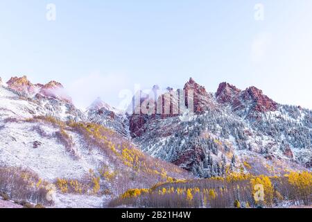 Blick auf den Sonnenaufgang von Maroon Bells in Aspen, Colorado Red Elk Mountains mit felsigen Bergen und Schnee im späten Herbst mit Nebelwolkenbedeckung für Winternebel Stockfoto