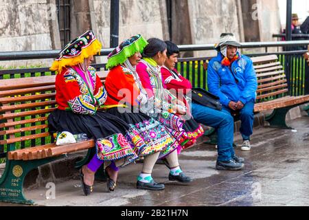 Frauen in traditioneller peruanischer Kleidung sitzen auf einer Bank in Cusco, im Heiligen Tal, Peru Stockfoto