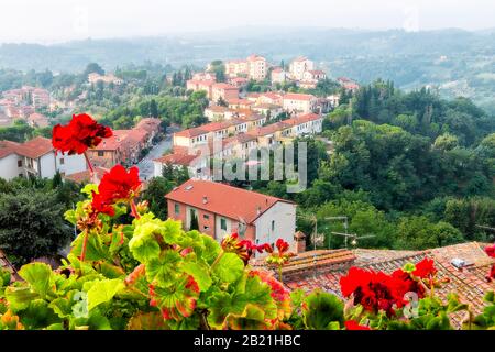 Chiusi Scalo beherbergt Gebäude in der Toskana, in der Stadt Italien und rote Geranienblüten im Garten im Vordergrund auf der Terrasse mit Blick auf die Landschaft Stockfoto