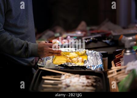 Kyoto, Japan People man Chefkoch, der in den Nishiki Market Shops kocht, Lebensmittelverkäufer, der Krabbenkuchen auf Spieß verkauft Stockfoto