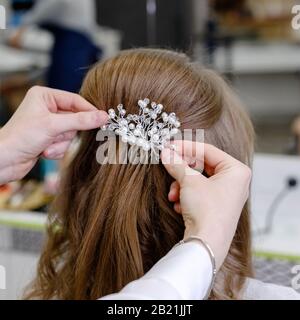 Haarschnitt Rückansicht mit Haarnadel. Friseursalon, der blonde Haarfrau mit langen Haaren im Schönheitssalon eine Frisur macht. Professionelle Haarpflege Stockfoto