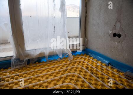 Gelbe Fußbodenheizung mit weißen Polyethylenrohren auf der Baustelle der neuen zweistöckigen Wohnung Stockfoto