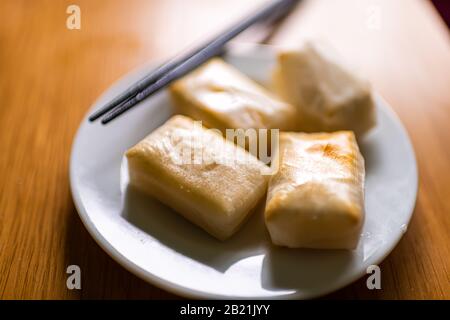 Mochi-Reiskuchen geröstet geröstet im Ofen auf traditionelle japanische Art und Weise auf Platte mit Essstäbchen gebacken Stockfoto