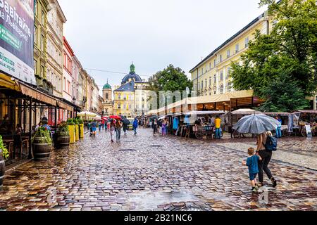 Lwiw, Ukraine - 31. Juli 2018: Historischer Blick auf die Dominikanische Kirche in der ukrainischen Lvov Stadt tagsüber auf Kopfsteinpflaster Straße und gelbes Gebäude auf dem Marktplatz Stockfoto