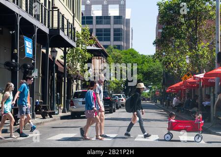 Mobile, USA - 21. April 2018: Menschen, die die Dauphin Straße der Altstadt in Alabama überqueren, berühmte Südstadt an sonnigen Tagen mit Restaurants Stockfoto